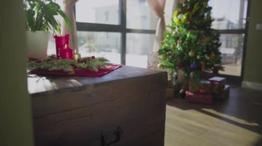 İki kırmızı mum ve bir altın mumu olan ebedi yeşil bir çelenk. Arka planda süslü bir Noel ağacı var. Noel arifesinde Hıristiyanların gelenek ve adetleri.