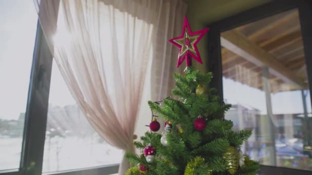 집 창문 옆에 장식된 크리스마스 트리가 있습니다. 새해. — 비디오