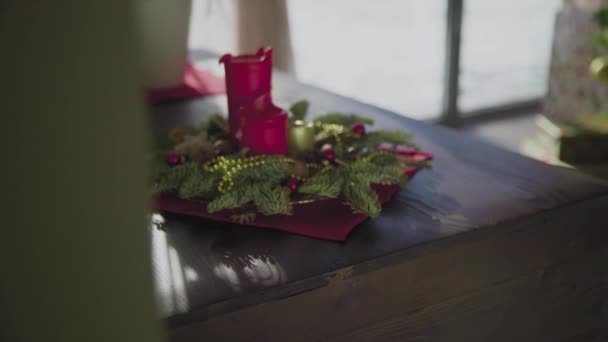 Une couronne à feuilles persistantes avec deux bougies rouges et une bougie dorée. Traditions et coutumes de Noël des chrétiens à la veille de la fête. — Video