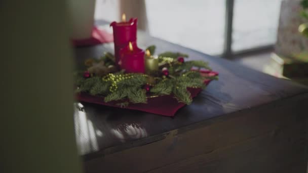 İki kırmızı mum ve bir altın mumu olan ebedi yeşil bir çelenk. Noel arifesinde Hıristiyanların gelenek ve adetleri. — Stok video
