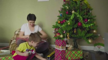 Bir anne ve çocuk güzel bir paket kağıdına hediye koyar. Noel zamanı. Şenlik havası.