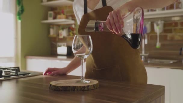 Een onherkenbare vrouw giet wijn uit een karaf in een prachtig glas. Close-up. — Stockvideo