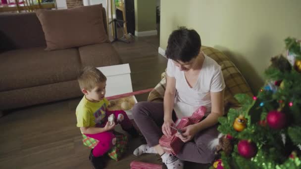 Una madre e un bambino confezionano un regalo in una bella carta da regalo. Natale. Umore festivo. — Video Stock