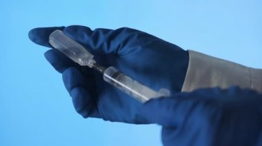 Doktorun elleri mavi arka planda aşı için aşı hazırlıyor.
