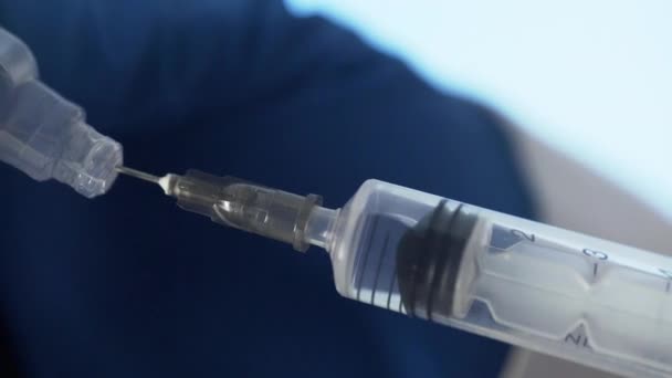 Крупним планом руки лікарів готують вакцину для ін'єкцій на синьому фоні — стокове відео