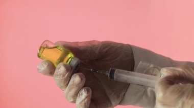 Doktorun elleri kırmızı arka planda aşı için aşı hazırlıyor.