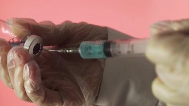 Doktorun elleri kırmızı arka planda aşı için aşı hazırlıyor.