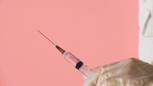 Крупним планом руки лікарів готують вакцину для ін'єкцій на червоному тлі — стокове відео