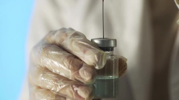 Крупным планом врачи держат в руках шприц с четким раствором и наливают красное вещество в ампулу. Процесс разработки вакцины, экспериментальные исследования в медицинской лаборатории — стоковое видео