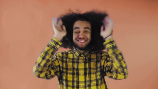 Mladý muž s afro účesem na oranžovém pozadí je šťastný. Emoce na barevném pozadí. — Stock video