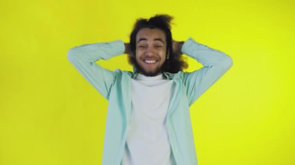 Mladý muž s afro účesem na žlutém pozadí je šťastný. Emoce na barevném pozadí. — Stock video