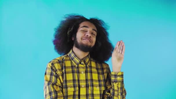 Bla, bla, bla. Een verveelde Afro-Amerikaan, gebaar met een blah-blah gebaar, moe van gesprekken en oninteressante informatie, poseren op een blauwe achtergrond — Stockvideo
