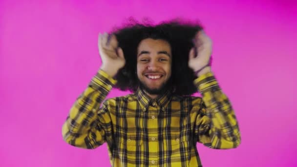 Un giovane con un'acconciatura africana su sfondo rosa è felice. Emozioni su sfondo colorato. — Video Stock