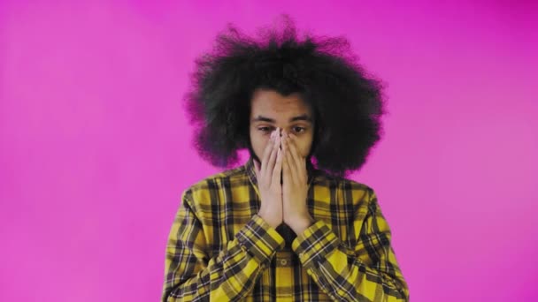 Un giovane con un'acconciatura africana su sfondo rosa è sorpreso. Emozioni su sfondo colorato. — Video Stock