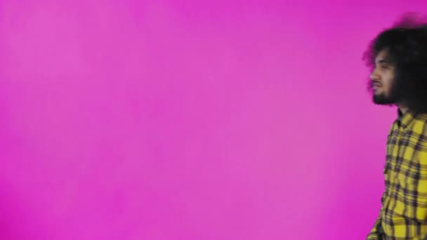Ένας νεαρός με αφρικάνικο χτένισμα σε ροζ φόντο βγάζει το κινητό του, κοιτάει το μήνυμα και το βάζει πίσω στην τσέπη του. Συναισθήματα σε έγχρωμο φόντο — Αρχείο Βίντεο