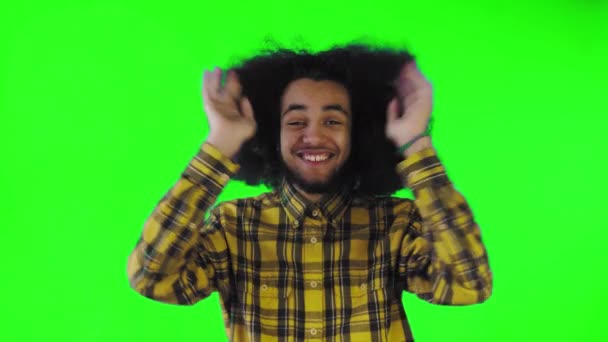 Egy afrikai frizurájú, zöld hátterű fiatalember boldog. Érzelmek egy színes háttér. — Stock videók