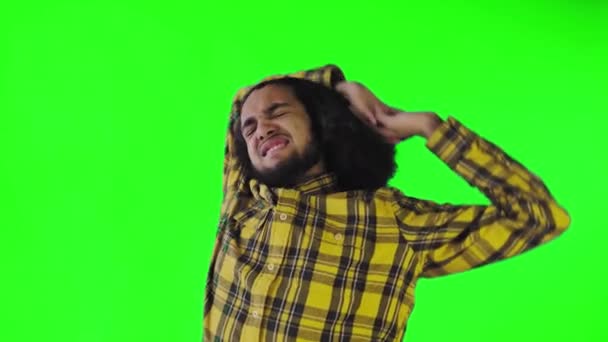Ein junger Mann mit afrikanischer Frisur auf grünem Hintergrund ist müde. Emotionen auf farbigem Hintergrund. — Stockvideo