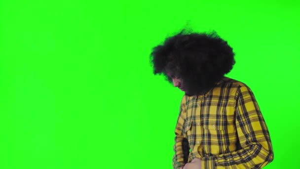 Um jovem com um penteado africano em um fundo verde tira o telefone, olha para a mensagem e coloca-a de volta no bolso. Emoções em um fundo colorido — Vídeo de Stock