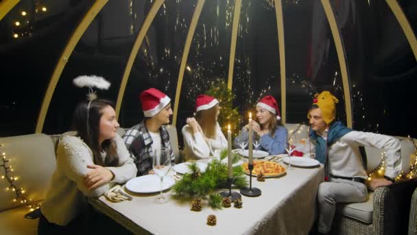 Friends celebrate New Year sitting at the dinner table. Students during a Christmas party at home. — Vídeo de Stock