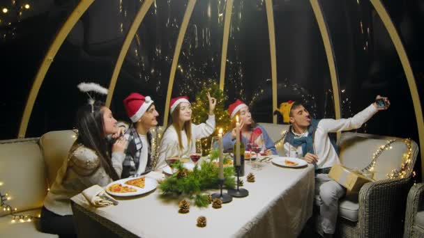 Friends celebrate the New Year at the dinner table. Students taking pictures on the phone during a Christmas party at home — 图库视频影像