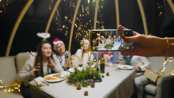 Close-up of the phone in the hands of a girl taking pictures of a group of friends for the New Year. — Video Stock