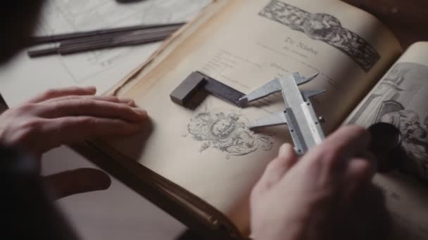 A close-up of the hands of a male jeweler measuring the size of the future product. A book on creating jewelry — стоковое видео