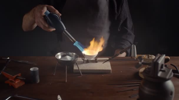 A male jeweler heats metal with a burner. Creating accessories — Stok video