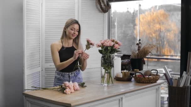 Uma jovem mulher bonita envolvida em floricultura começa a recolher as melhores flores para o seu arranjo de flores. Floricultura — Vídeo de Stock