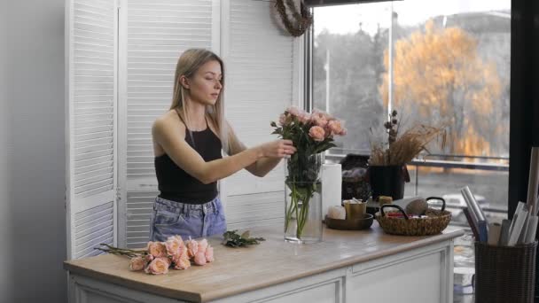 Uma jovem mulher bonita envolvida em floricultura começa a recolher as melhores flores para o seu arranjo de flores. Floricultura — Vídeo de Stock