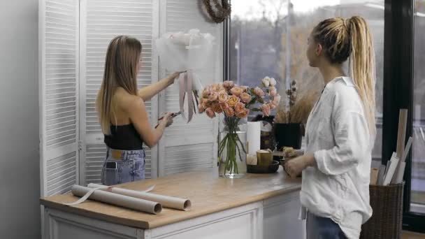 A young beautiful woman engaged in floristry gives a bouquet of flowers to a client. Floristry — Stok video