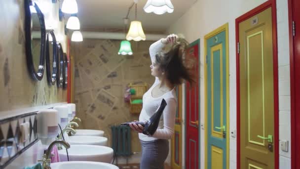 Una joven se seca el pelo con un secador de pelo en un hotel — Vídeos de Stock