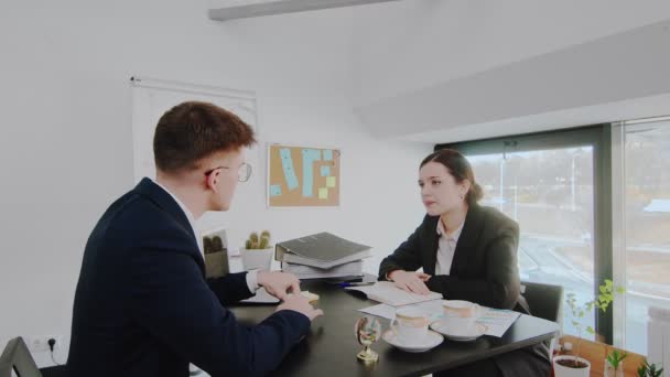 ビジネスマンと女性は、テーブルに座ってビジネス上の問題を解決します。実業家 — ストック動画