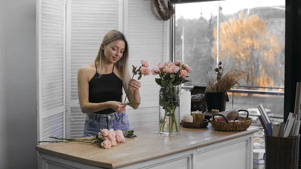 Eine junge schöne Frau, die sich mit Floristik beschäftigt, beginnt, die besten Blumen für ihren Blumenschmuck zu sammeln. Floristik — Stockfoto