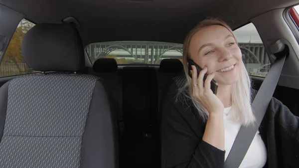 The girl driving the car is talking on the phone. People are driving in a car — Φωτογραφία Αρχείου