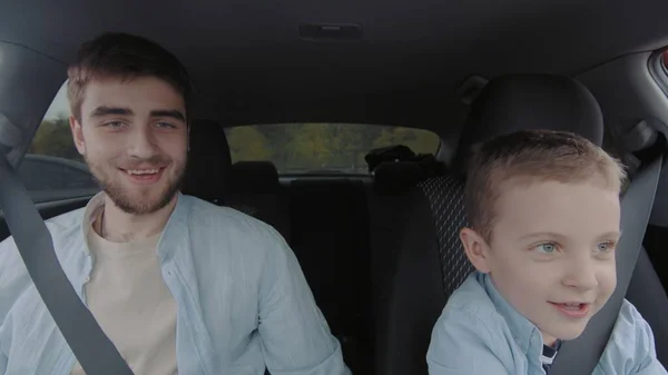 A guy and a little boy are sitting in a car. People in the car — 图库照片