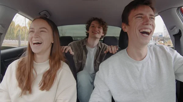 Un pequeño grupo de personas se ríe y monta en un coche. La gente está conduciendo en un coche Fotos de stock