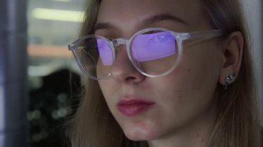A close-up of a girl with glasses, her glasses reflect an Online Stock Market Chart Showing the Bivisand Bullish Trend of Bitcoin currency. In real time.