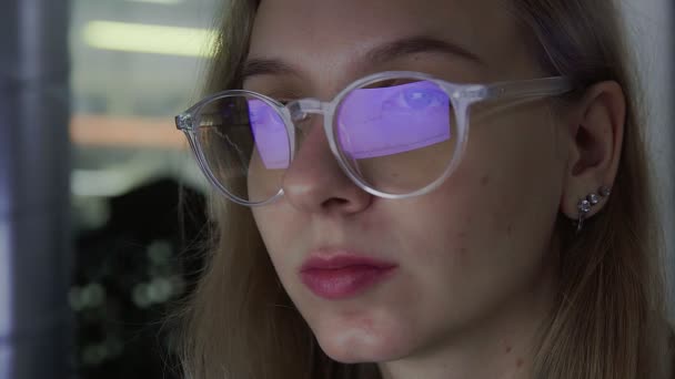 Un primer plano de una chica con gafas, sus gafas reflejan un gráfico del mercado de valores en línea que muestra la tendencia alcista bivisand de Bitcoin moneda. En tiempo real. — Vídeo de stock