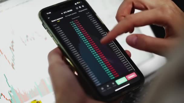 Dívka drží telefon s on-line burzovní graf ukazuje medvědí a býčí trendy Bitcoin měny. V reálném čase. — Stock video