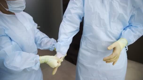 Médicos profesionales en uniforme, vestidos con batas con corbatas en la parte posterior, se están preparando para la operación. Medicina — Vídeos de Stock