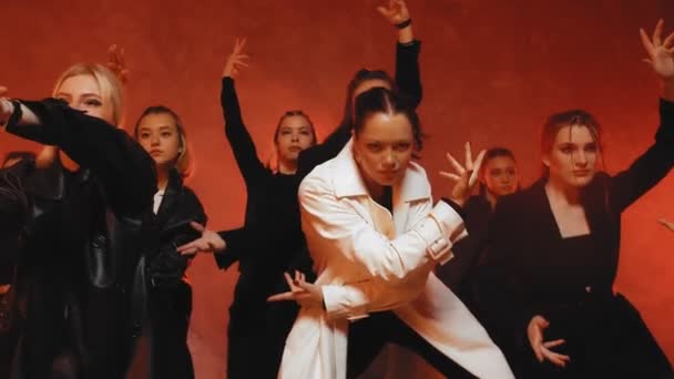 Un grupo de hermosas chicas bailando en una habitación con iluminación roja en trajes negros. Bailes — Vídeos de Stock