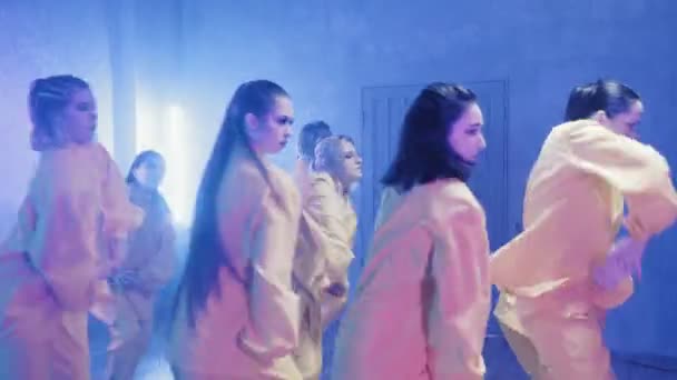 Un gruppo di belle ragazze che ballano in una stanza con illuminazione blu in abiti gialli. Danze — Video Stock