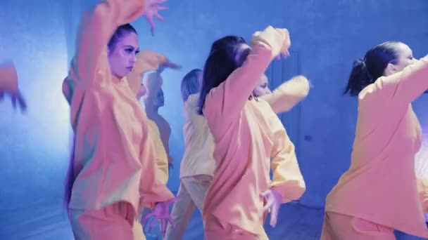 Een groep mooie meisjes dansend in een kamer met blauwe verlichting in gele pakken. Dansen — Stockvideo