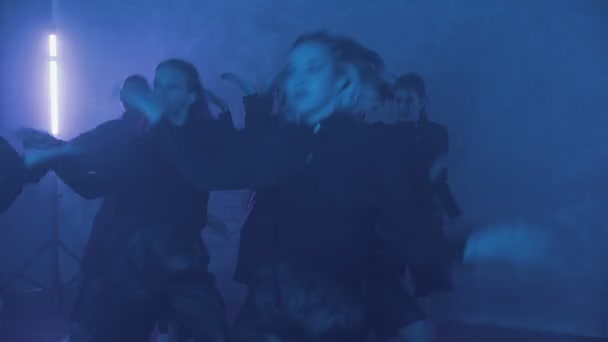 A group of beautiful girls dancing in a room with blue lighting in black suits. Dances — Stockvideo