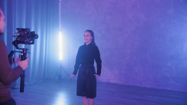 A beautiful girl is dancing in a room with blue lighting in a black suit. The cameraman shoots a dancing girl. Dances — Video Stock