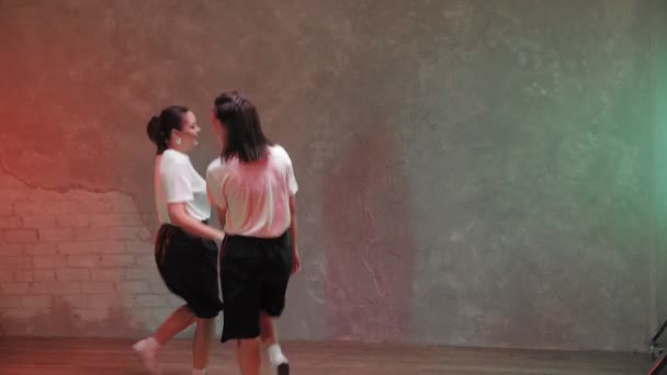 Two beautiful girls are dancing in a room with red and green lighting and. Dances — Αρχείο Βίντεο