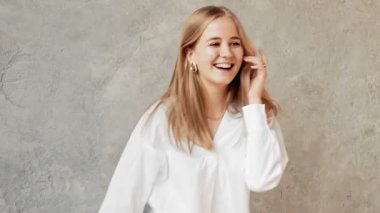 A beautiful girl in a white shirt is dancing indoors. Dances