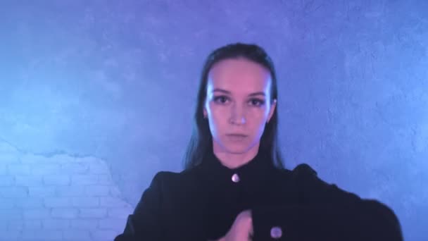 A beautiful girl is dancing indoors under blue lighting in a black suit. Dances — Stockvideo