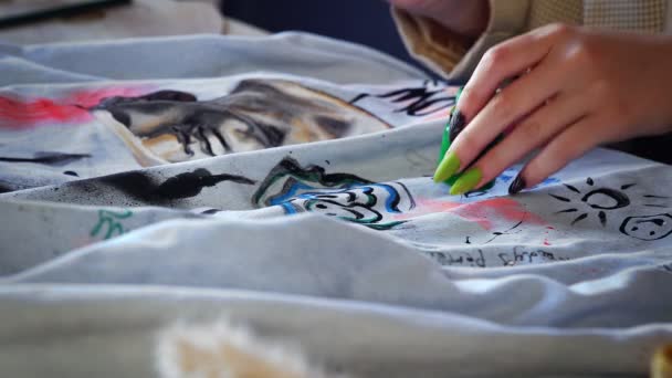 Primer plano de una hermosa chica pelirroja dibujando con pinturas multicolores en la ropa. Trabajo hecho a mano — Vídeos de Stock