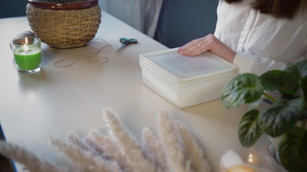 Ein schönes Mädchen im weißen Hemd holt eine Schachtel mit Perlen hervor. Handarbeit — Stockvideo